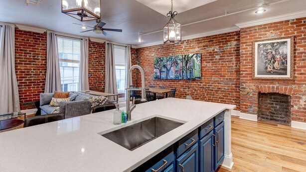 A modern kitchen with a large island, a fireplace, and a dining area. - Elegant 2BR condo 3 blocks to French Quarter. King suite, garage parking, walk to Bourbon. (New Orleans)