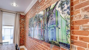 A hallway with a brick wall and a large mural of a green building. - Elegant 2BR condo 3 blocks to French Quarter. King suite, garage parking, walk to Bourbon. (New Orleans)