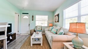 A living room with a sofa, a television, a lamp, and a door.