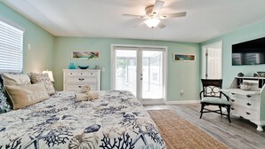 A bedroom with a bed, a dresser, a chair, and a ceiling fan.