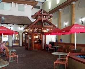 Un café interior con sombrillas rojas, una cafetería y suelo de ladrillo.