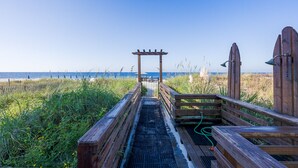 A wooden boardwalk leading to a beach with a wooden archway and a metal gate. - Beach Perfect Top of the Gulf 625-Beautiful Modern Beachfront Studio-Perfect Place in Paradise! (Panama City Beach)