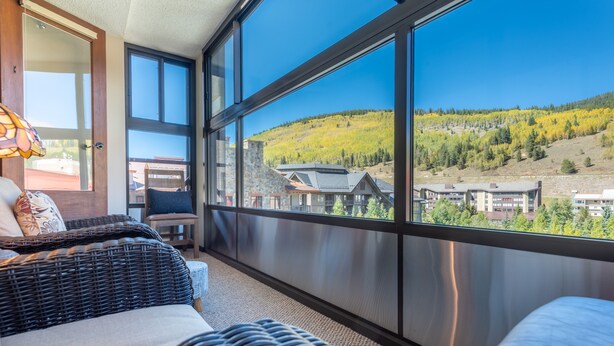 A balcony with wicker furniture, large windows, and a view of a mountainous landscape. - Amazing condo next to the American Eagle lift.  Free WiFi, Free Parking (copper mountain)