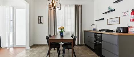 A modern kitchen with a dining table, chairs, a coffee sign, and a kitchen island with appliances.