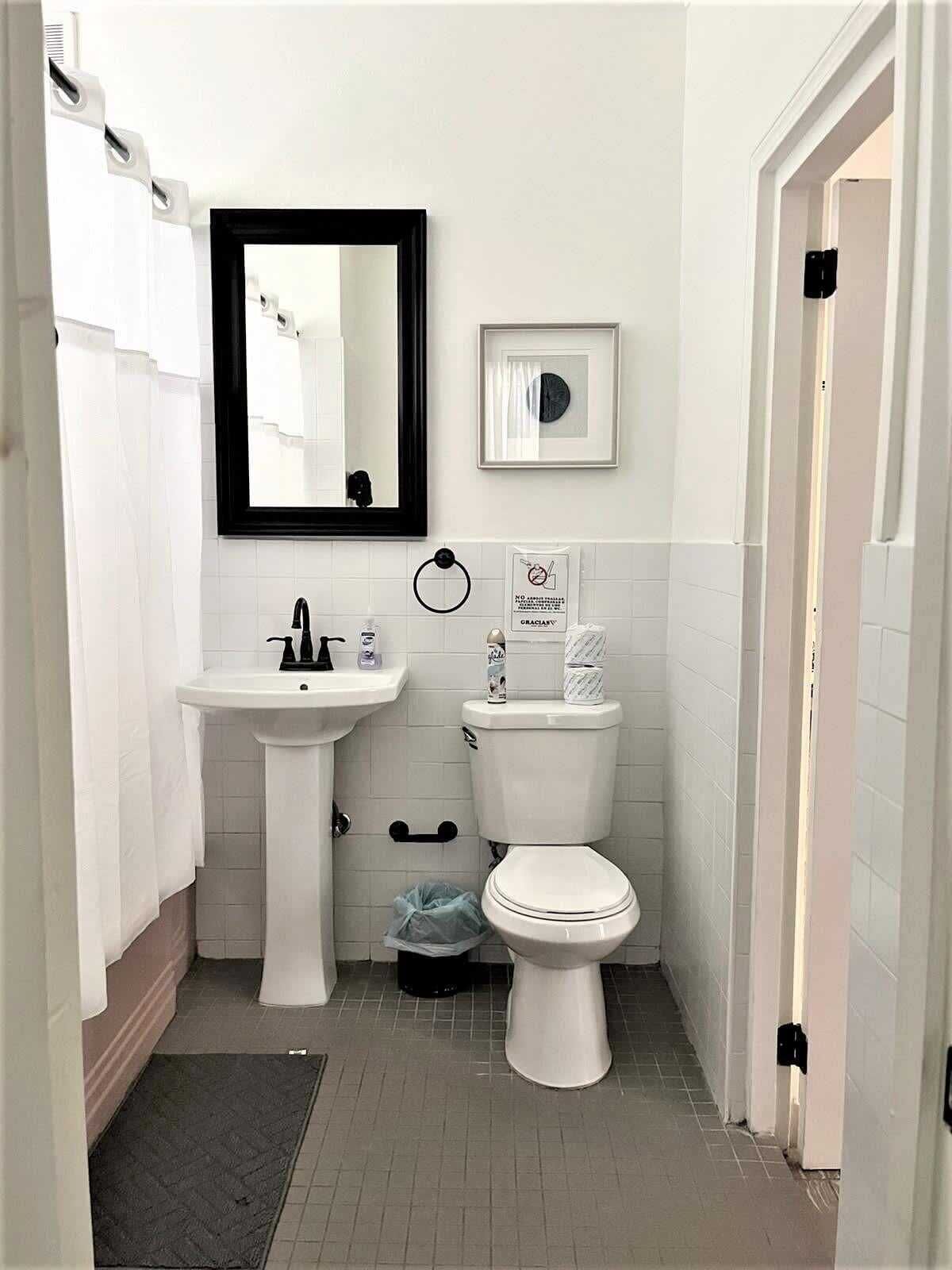 A compact bathroom with a pedestal sink, a toilet, and a mirror.