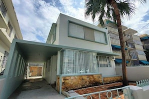 A modern two-story building with a stone facade, large windows, and a visible balcony. - 8BR | 7.5BA | Sleeps 16+ | Wi-Fi | Walk to Beach (San Juan)