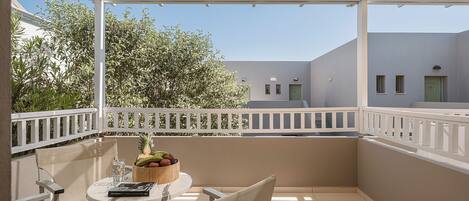 A balcony with a table, chairs, a fruit bowl, and a book.