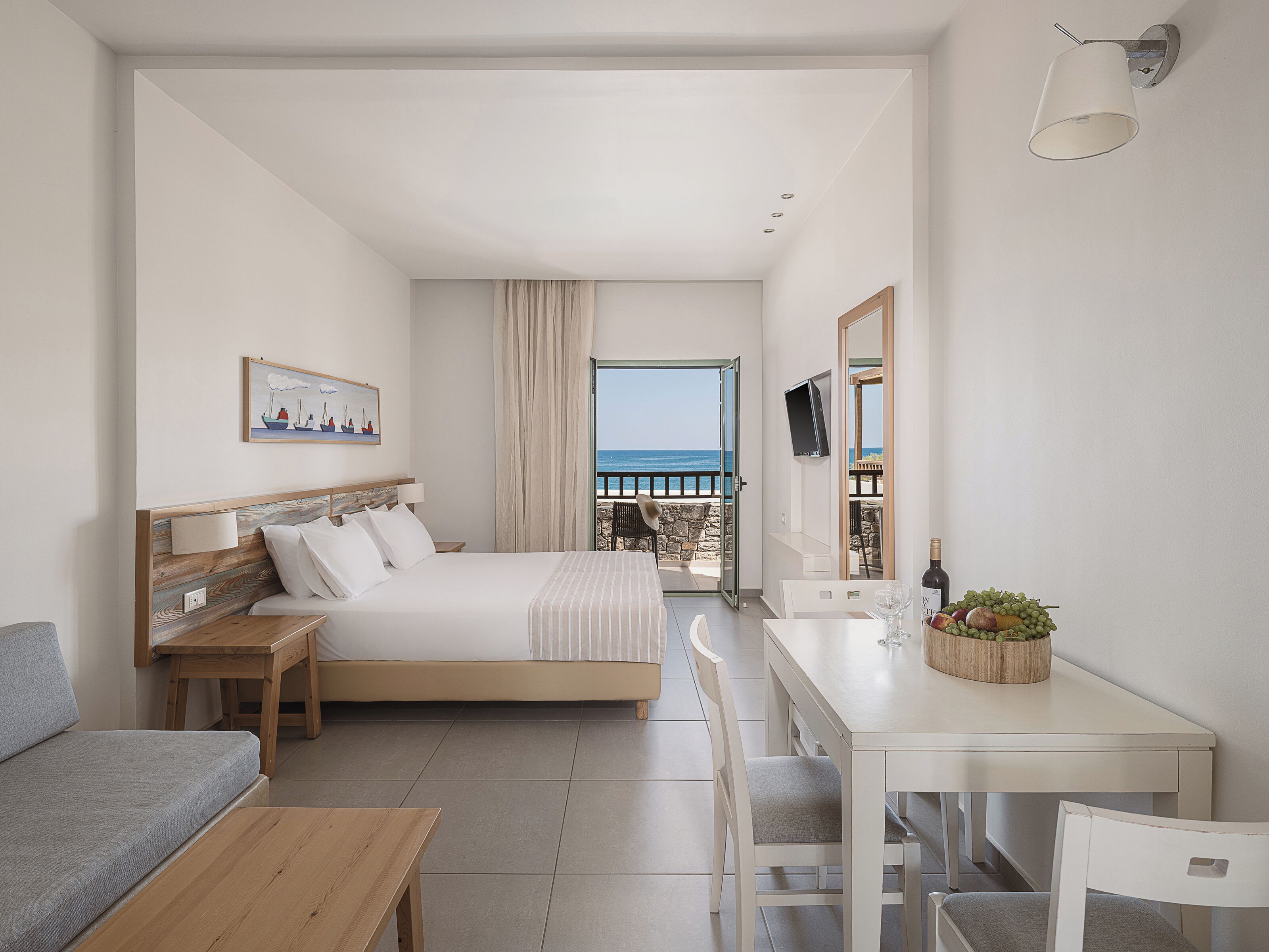 Habitación de hotel moderna con cama, escritorio, sofá y vista al mar.