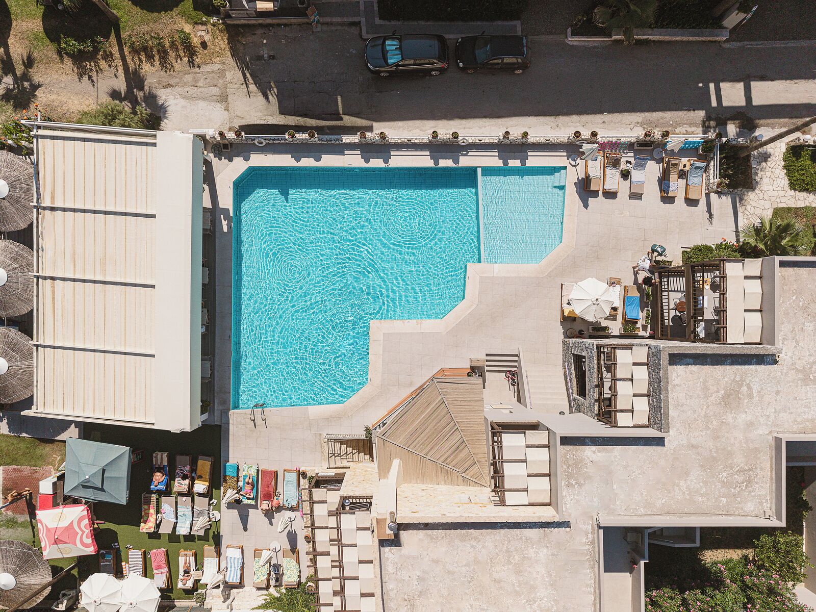 Una piscina en la azotea con sillones de descanso y sombrillas.