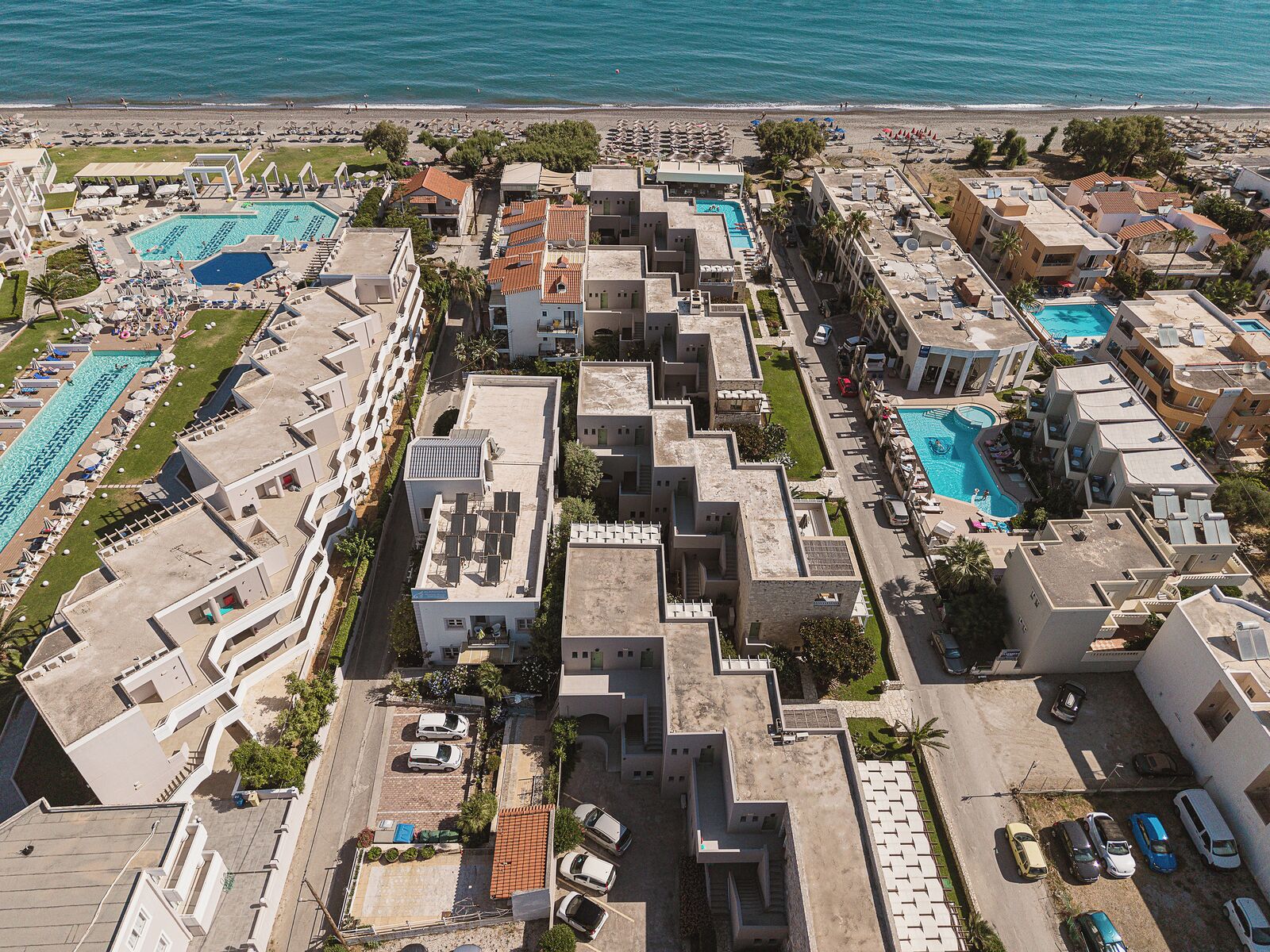 A resort with multiple swimming pools, a beach, and a parking area.