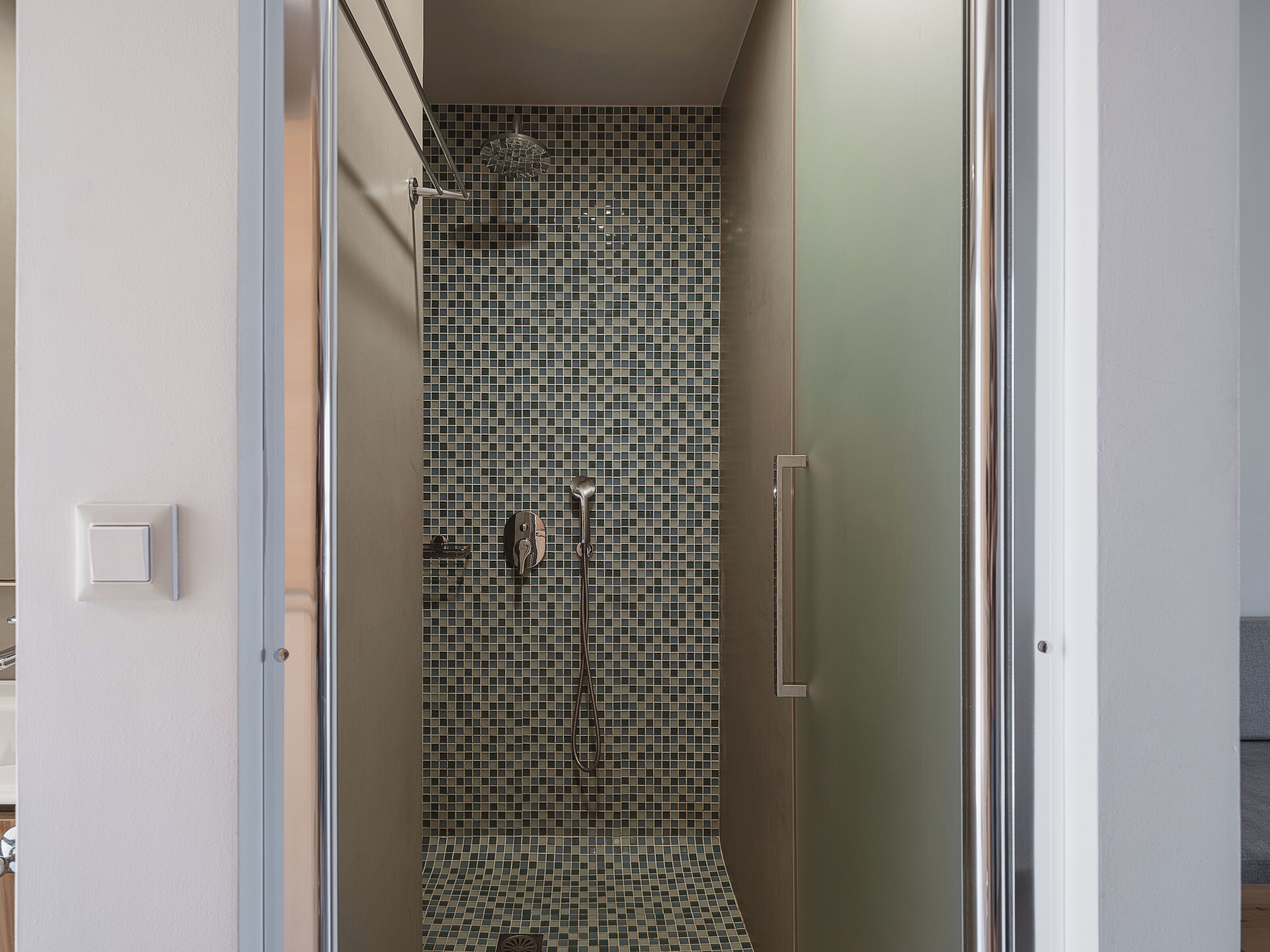 Una ducha con pared de azulejos y puerta de cristal.