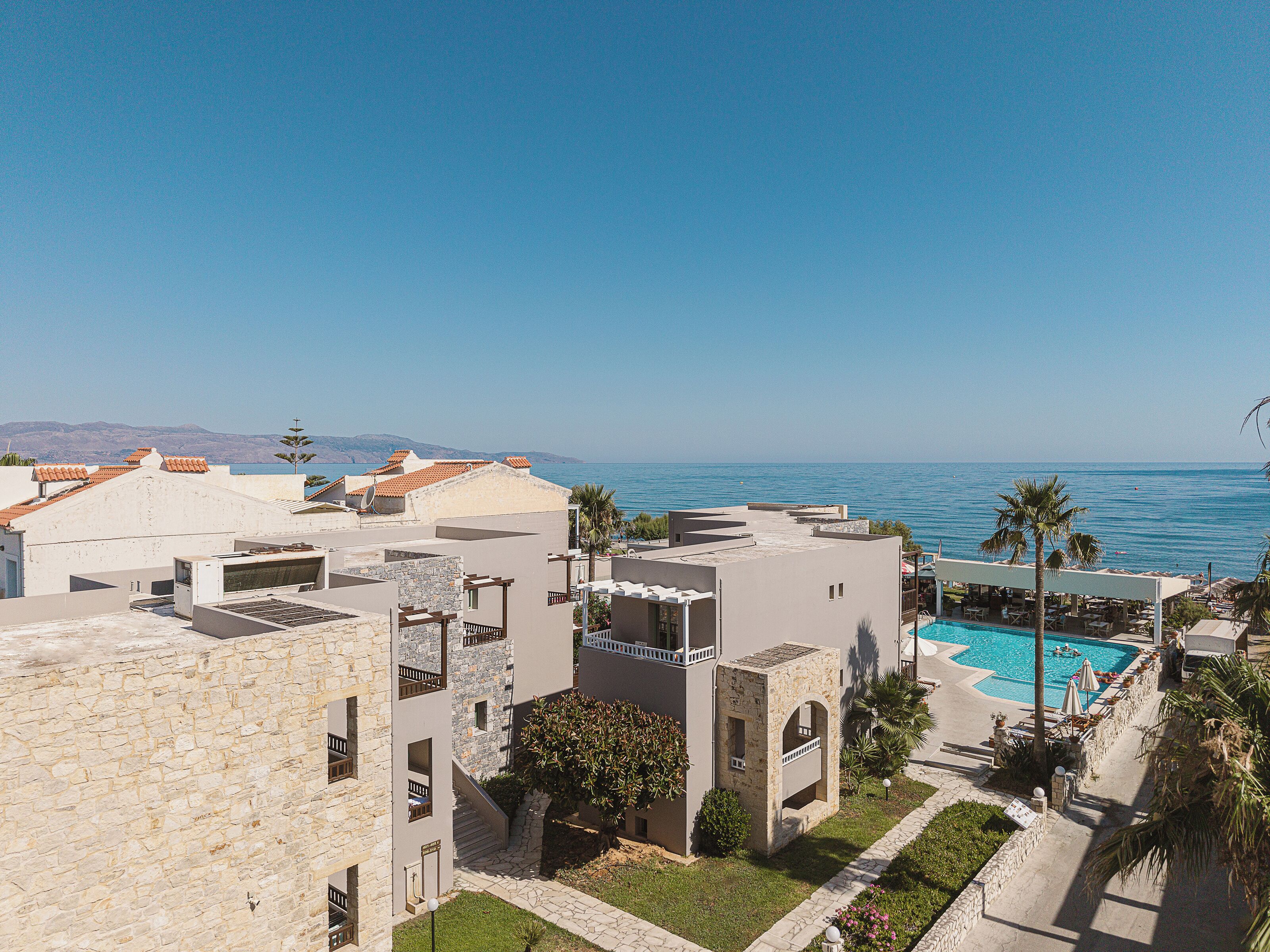 Un resort con piscina, edificios de piedra y vista al mar.