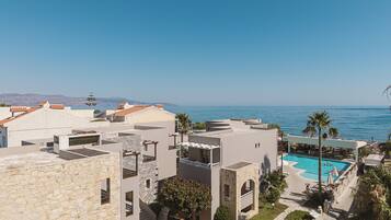 A resort with a pool, stone buildings, and a view of the sea.