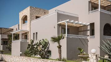 A modern building with a stone facade, multiple balconies, and a courtyard with cacti and palm plants.