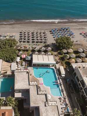 A resort with a swimming pool, beach umbrellas, and lounge chairs. - Erato Beach Hotel Adults Only (Platanias)
