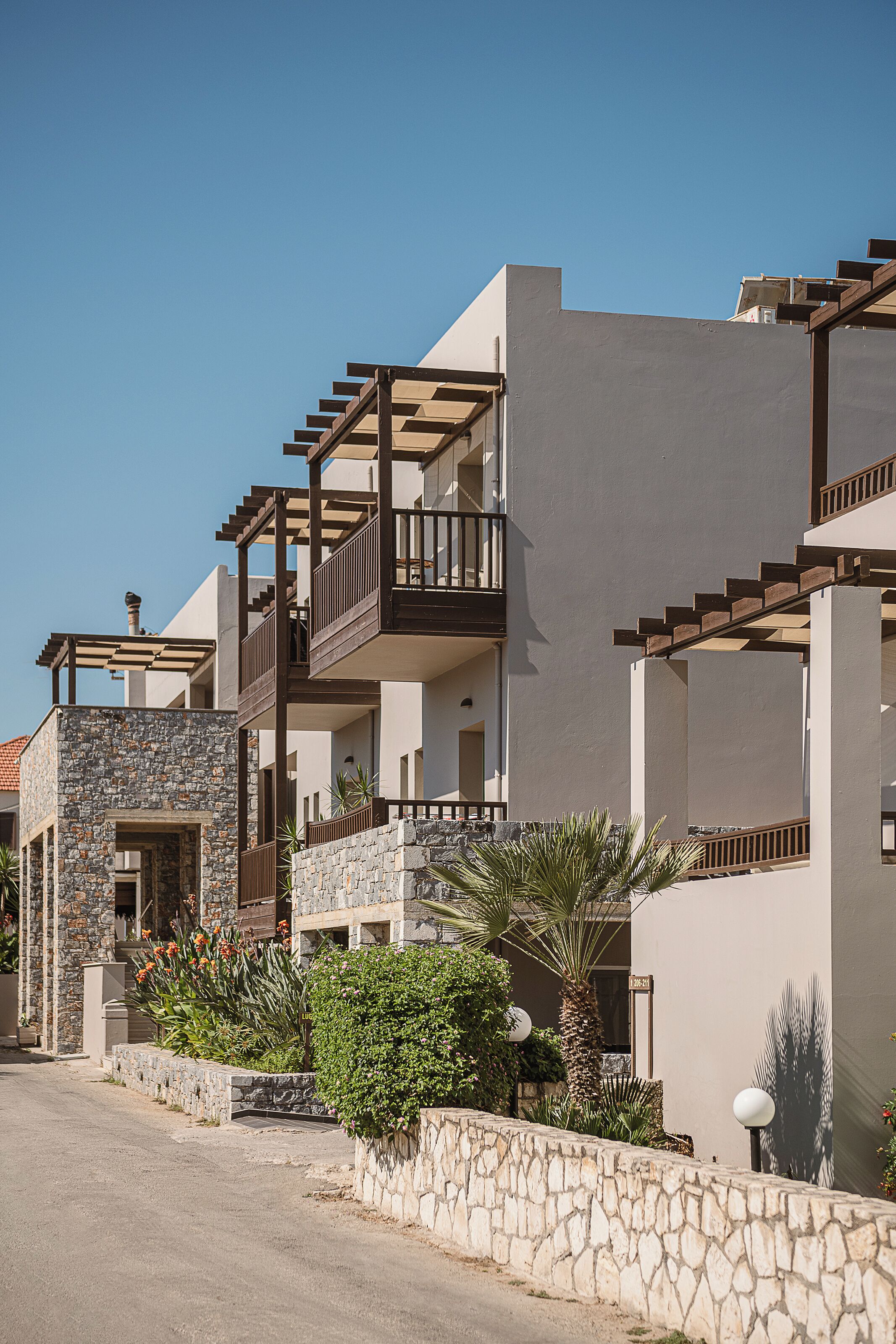 Un edificio residencial con varios balcones, muros de piedra y cielo despejado.