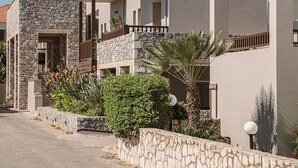 A residential building with multiple balconies, stone walls, and a clear sky. - Erato Beach Hotel Adults Only (Platanias)