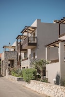 A residential building with multiple balconies, stone walls, and a clear sky.