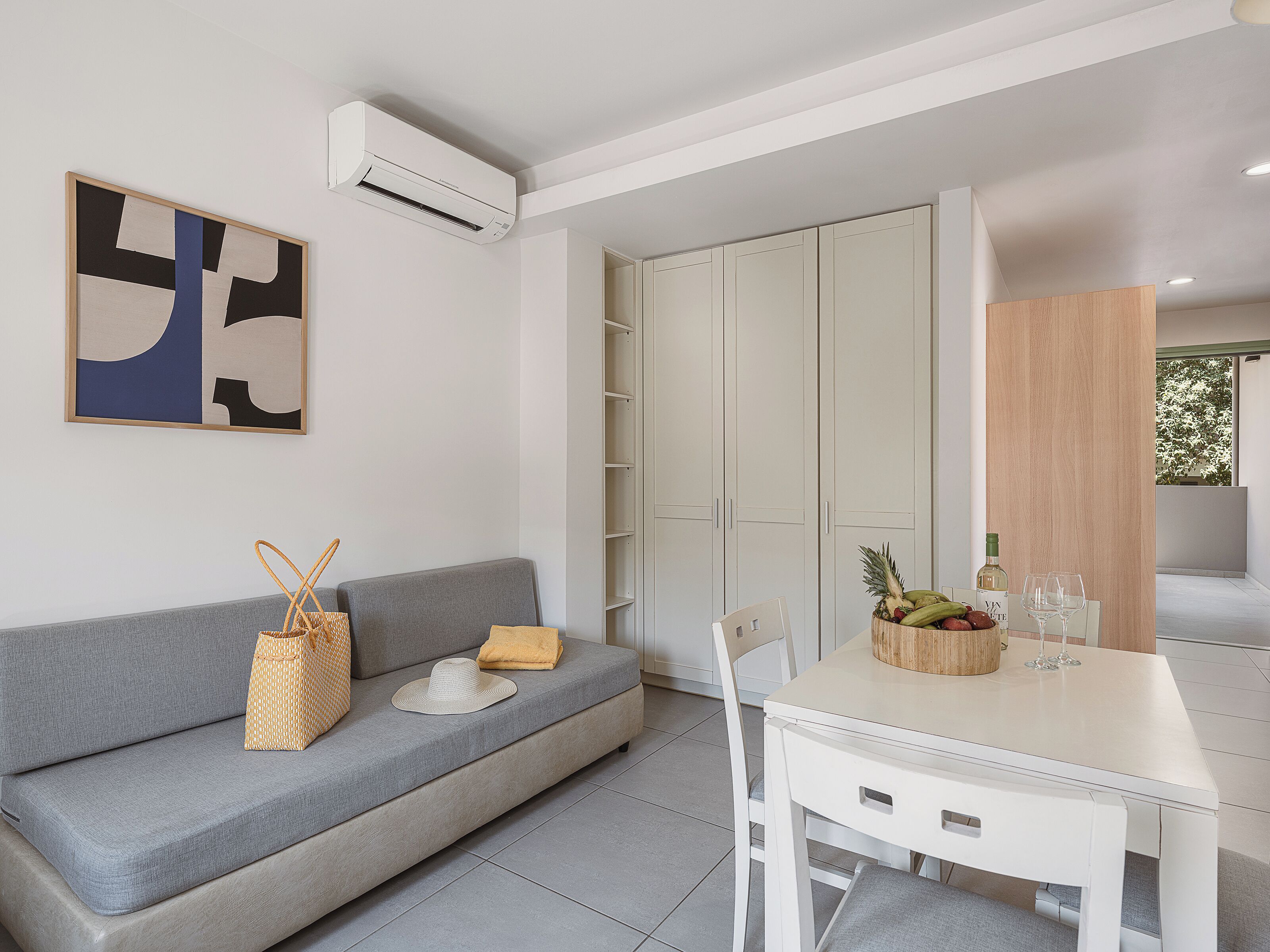 A modern living space with a grey sofa, a white table, and a fruit bowl.