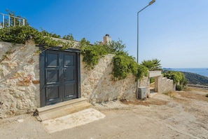A stone building with a dark door, steps leading up to it, and a clear view of the landscape in the background.