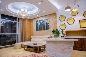 A modern living room with a marble coffee table, a sofa, and a dining area with a kitchen counter. - Shuangzixing Hotel (Mojiang)