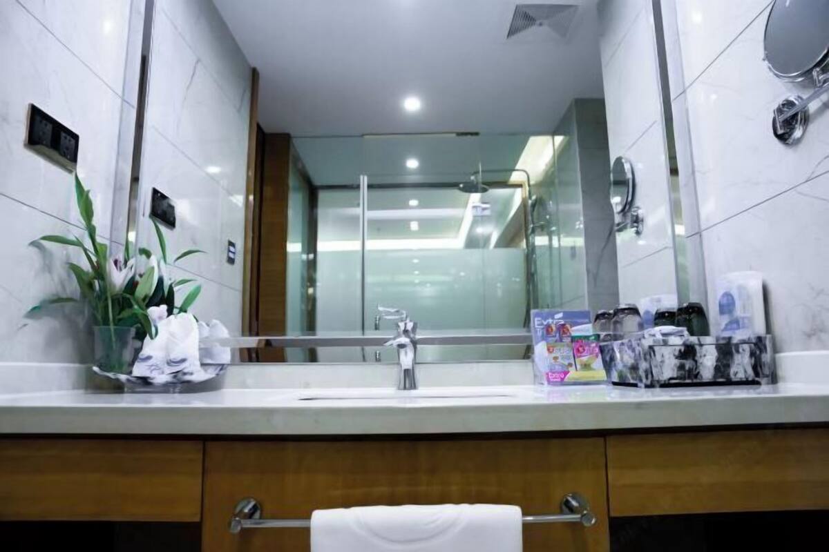 A modern bathroom with a large mirror, a sink, and a towel rack.