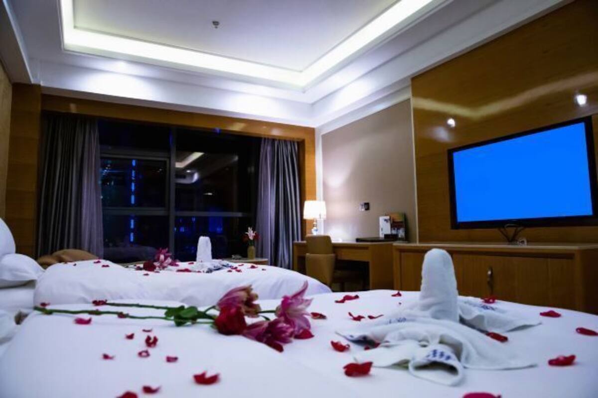 A hotel room with a bed, a TV, and a desk with a chair.