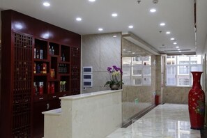 A reception area with a marble counter, a decorative vase, and a reception desk. - Shuangzixing Hotel (Mojiang)