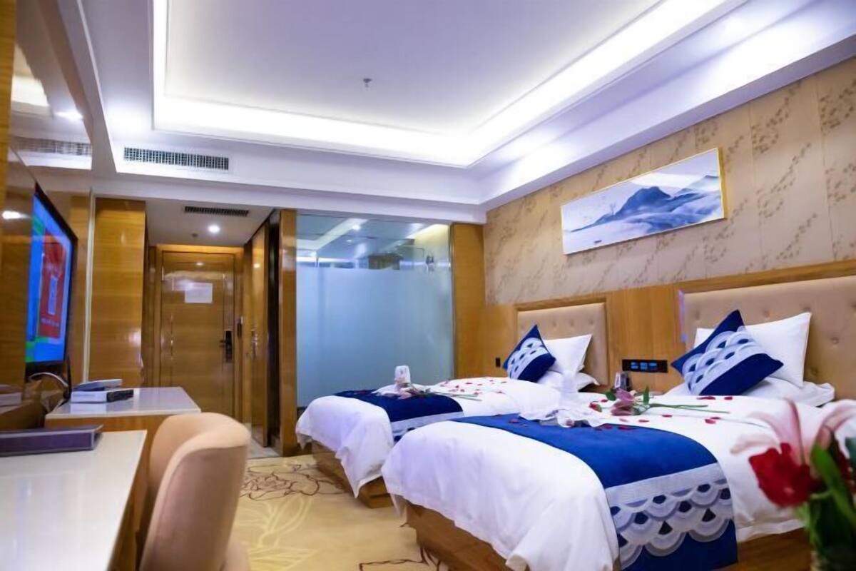 A hotel room with two beds, a desk, and a television.
