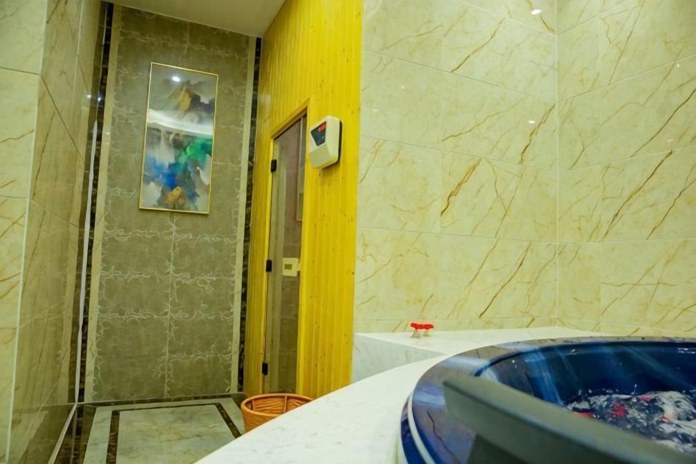 A bathroom with a bathtub, a shower area, and a marble wall.