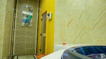 A bathroom with a bathtub, a shower area, and a marble wall.