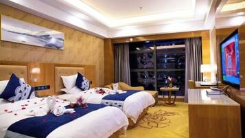 Habitación de hotel con dos camas, televisión, escritorio y ventana grande.
