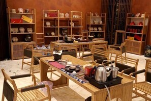 Ein traditionelles Teehaus mit Holzsitzmöbeln, Regalen voller Teekannen und einem Tisch, der für eine Teezeremonie gedeckt ist.