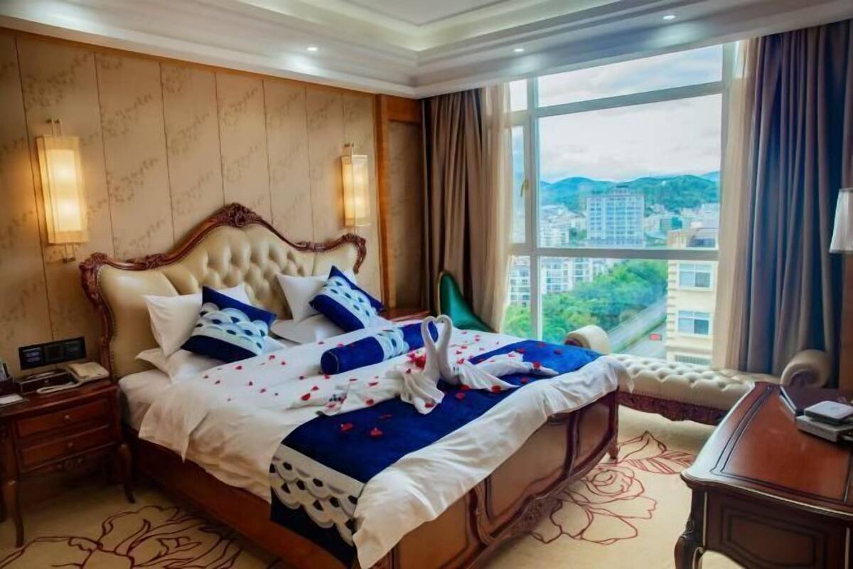 A hotel room with a large bed, a desk, and a view of the city.