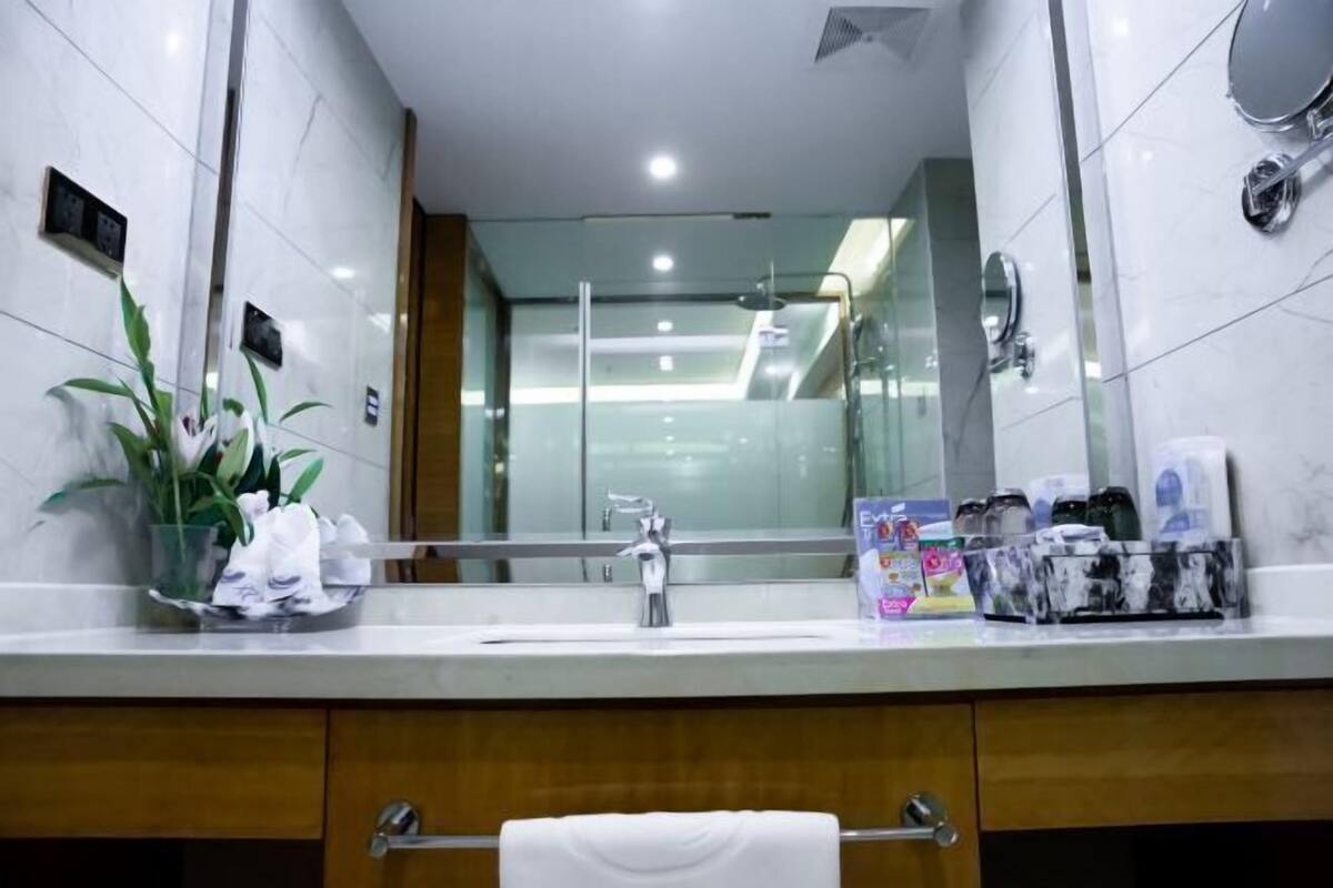 A modern bathroom with a large mirror, a sink, and a towel rack.