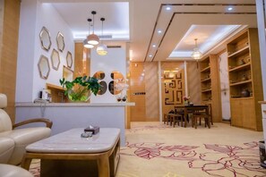 A hotel lobby with a reception desk, seating area, and a dining table. - Shuangzixing Hotel (Mojiang)