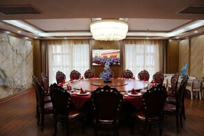 A conference room with a round table, chairs, a chandelier, and a television screen. - Shuangzixing Hotel (Mojiang)