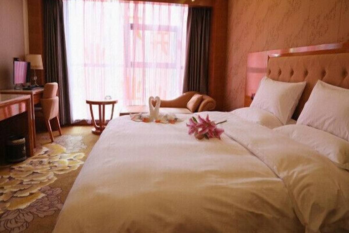 A hotel room with a large bed, a desk, a chair, and a small table.