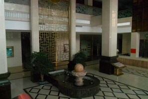 Un vestíbulo con una fuente central, una pared decorativa y un mostrador de recepción.