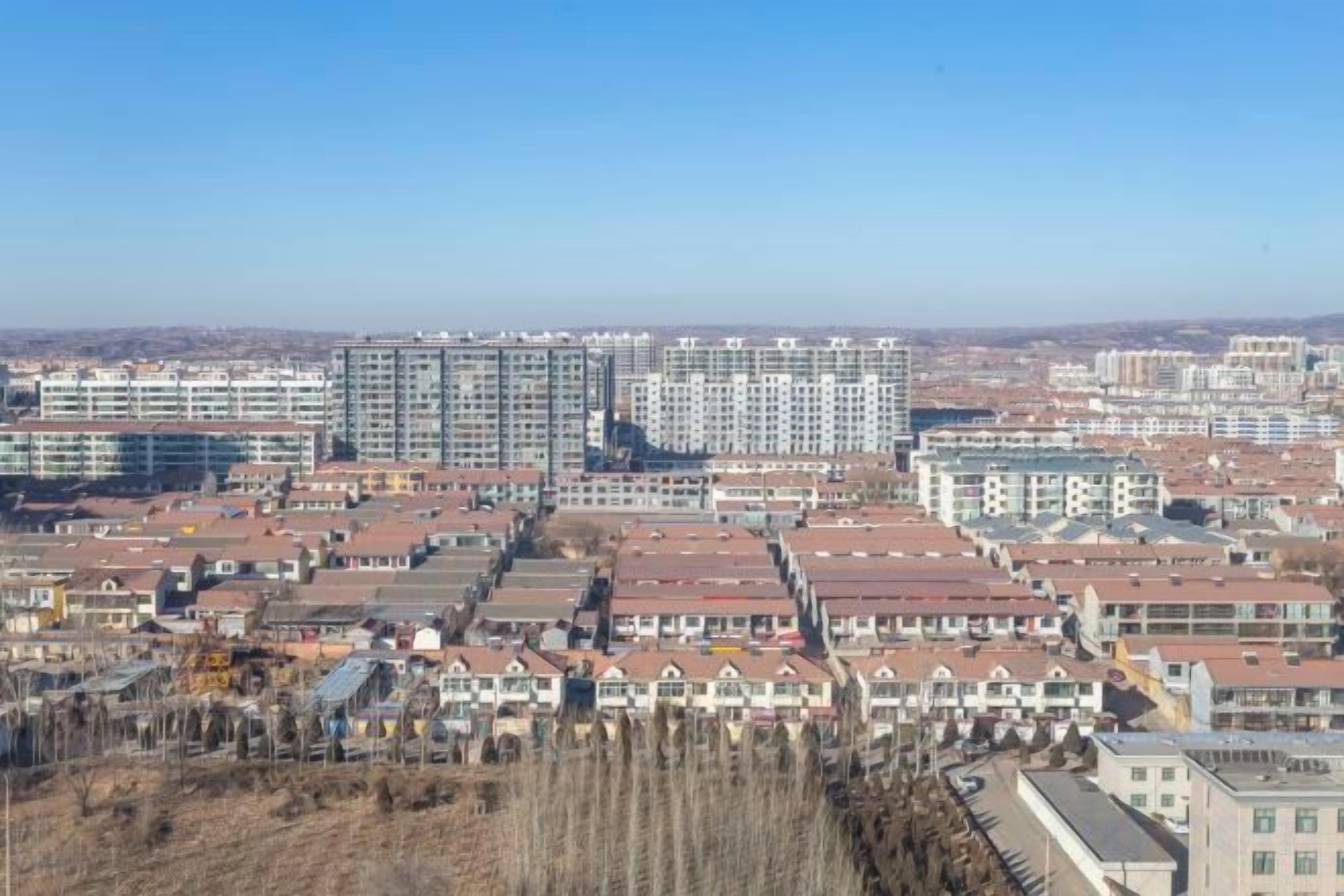 A residential area with multiple apartment buildings and houses, featuring a variety of roof styles and building heights.