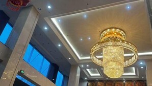 A chandelier in a hotel lobby with a high ceiling and recessed lighting. - Jinxin Hotel (Xiangyuan)