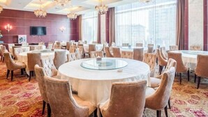 A conference room with round tables, chairs, chandeliers, and large windows. - Jinxin Hotel (Xiangyuan)