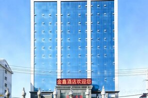 A tall hotel building with a blue facade and a red sign at the entrance. - Jinxin Hotel (Xiangyuan)