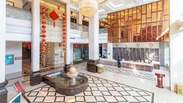 A spacious lobby with a central fountain, a chandelier, and a seating area with a long table. - Jinxin Hotel (Xiangyuan)