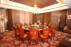 Uma sala de jantar formal com uma mesa redonda, cadeiras e um lustre.