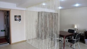 A room with a partition, a table, chairs, a lamp, and a door. - Fubang Hotel Apartment (Suifenhe)