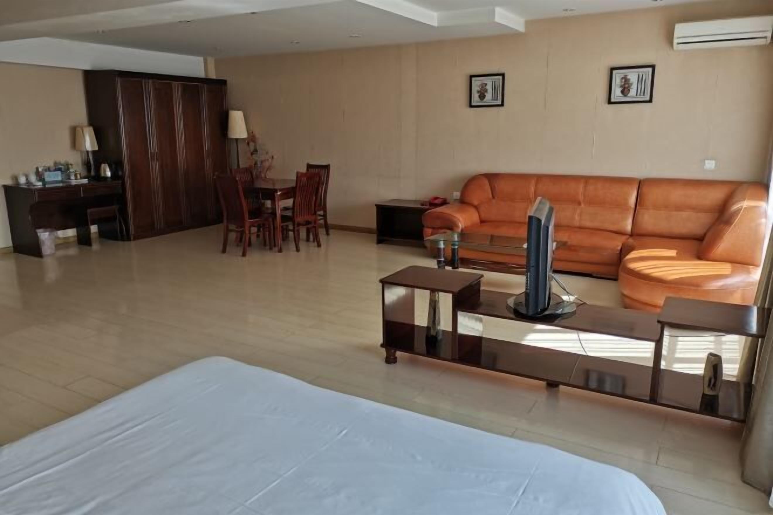 Amplia sala de estar con un sofá, una mesa de centro y un televisor. Se observa un comedor con sillas y una mesa.