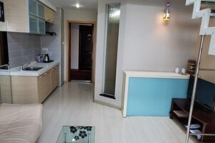 A compact living space with a kitchenette, a small seating area, and a television.