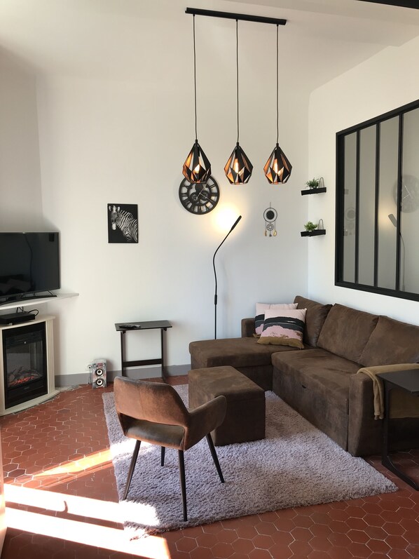 Un soggiorno moderno con un divano componibile, un caminetto, una TV a schermo piatto e decorazioni murali.