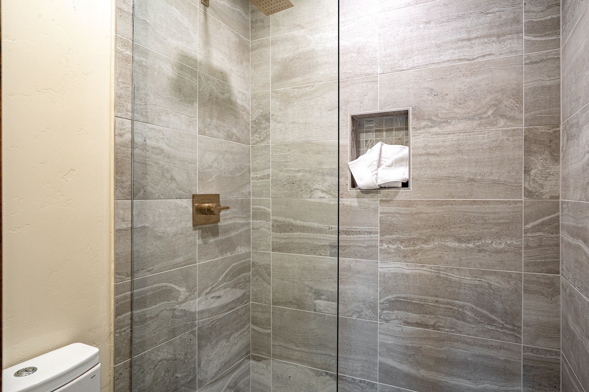 A shower with a glass door and a towel rack.